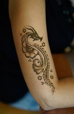 a woman's arm with a tattoo on it and flowers around the arm area