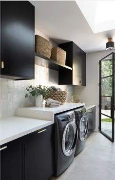 a washer and dryer in a room with black cabinets, white counter tops