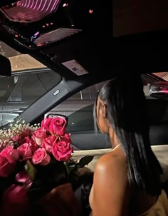 a woman sitting in the back seat of a car with pink roses