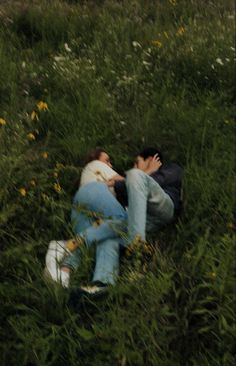 two people laying on the ground in tall grass