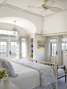 a large white bed sitting in a bedroom next to two windows