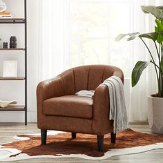 a brown chair sitting on top of a wooden floor next to a potted plant