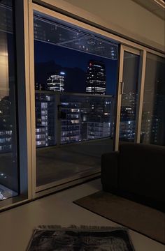 a living room filled with furniture and a large window overlooking the city lights at night