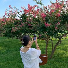 a woman taking a photo of a flowering tree