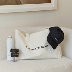 a tote bag sitting on top of a white couch next to a bottle of water