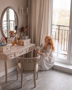 a woman sitting on the floor in front of a desk with a mirror and vanity