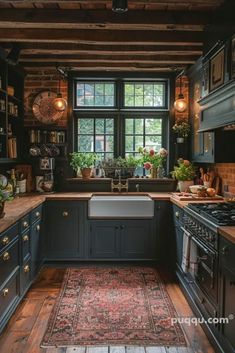 a kitchen with black cabinets and wooden floors, an area rug on the floor is in front of the window