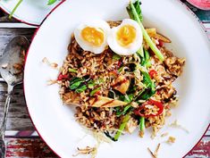 a white plate topped with rice, asparagus and hard boiled eggs