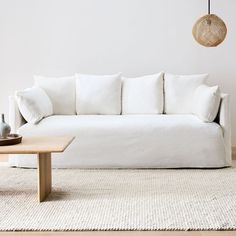 a white couch sitting on top of a wooden table in front of a white wall