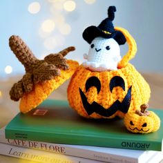 there is a crocheted pumpkin and a stuffed animal on top of some books