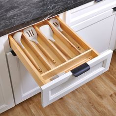 an open drawer with utensils and spoons in it on a counter top