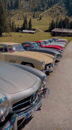 a row of old cars parked next to each other on the side of a road