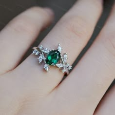 a woman's hand with an emerald and diamond ring