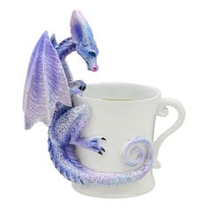 a blue dragon figurine sitting on top of a white coffee cup with its wings spread