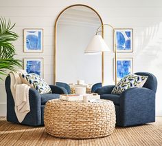 a living room with two blue chairs and a coffee table in front of a large mirror