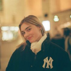 a woman in a black and white jacket smiles at the camera