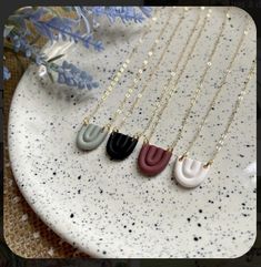 three different necklaces on a plate with flowers in the background