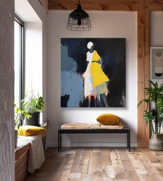 a painting hangs on the wall above a bench in a room with wood flooring