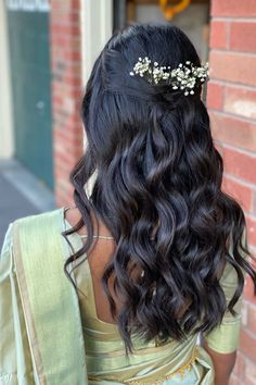 the back of a woman's head with long hair and flowers in her hair