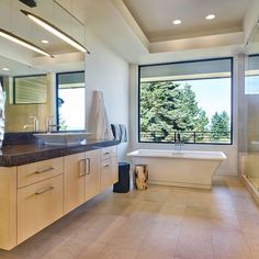 a large bathroom with two sinks and a bathtub in front of a big window