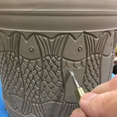 a person is using a paintbrush to decorate a pot with decorative designs on it