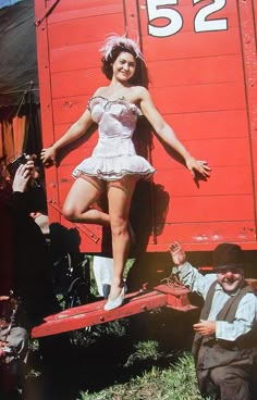 a woman standing on the back of a red train car