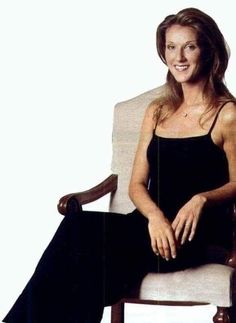 a woman is sitting in a chair with her legs crossed and smiling at the camera