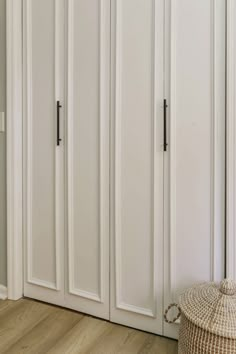 an empty room with white doors and wooden flooring, including a basket on the floor