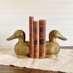 three books are stacked on top of each other in front of a gold duck bookend