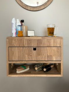 a wooden shelf with some items on it and a mirror above it that has a clock