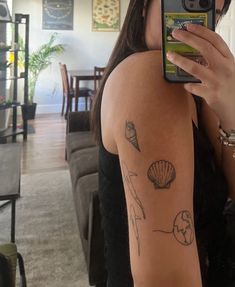 a woman taking a selfie with her cell phone in front of her arm and tattoos on the back