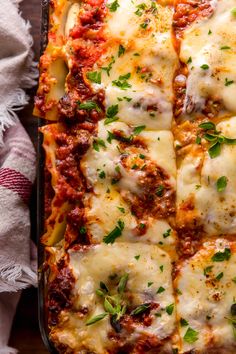 a casserole dish with meat and cheese in it on a table next to a napkin