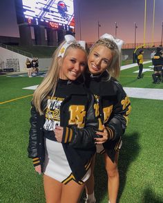 two cheerleaders pose for a photo on the field