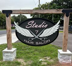 a sign that says studio 7 hair salon in front of some grass and trees with scissors on it