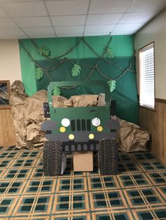 a large green truck made out of cardboard sitting on top of a carpeted floor