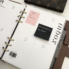 an open planner book sitting on top of a desk next to a wallet and purse