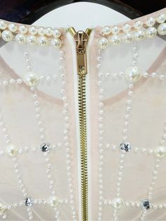 a close up of a white dress with pearls on the front and zippers at the back