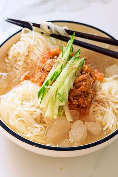 a bowl filled with noodles, meat and veggies on top of a table