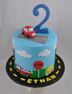 a blue two - tiered birthday cake with cars on it