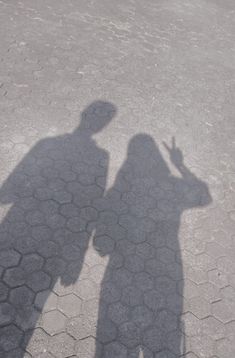 the shadow of a man holding a cell phone in his hand and standing next to him