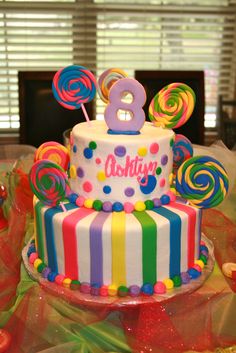 a birthday cake decorated with lollipops, candy and the number eight on top