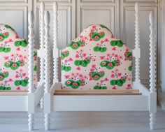 two white chairs with pink and green floral upholstered backrests, one in the shape of a headboard