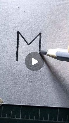 someone is drawing the letter m on a piece of paper with a pencil and crayon