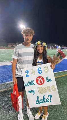 a man and woman standing next to each other on a field holding a sign that says, how do my hoco date?