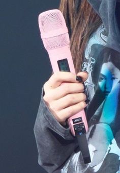 a woman holding a pink hair dryer in her right hand while wearing a hoodie