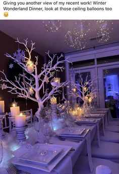 a table set with white plates and silverware, lit up by candlelight trees