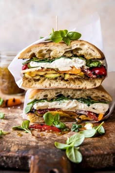 three sandwiches stacked on top of each other with basil leaves and cheese in the middle