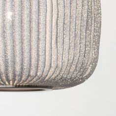 a close up of a light fixture with beads on it's side and a white wall in the background