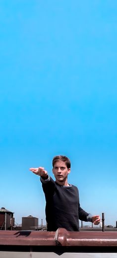 a man standing on top of a metal rail holding his hand out to the side