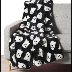 a black and white teddy bear blanket sitting on top of a couch next to a chair